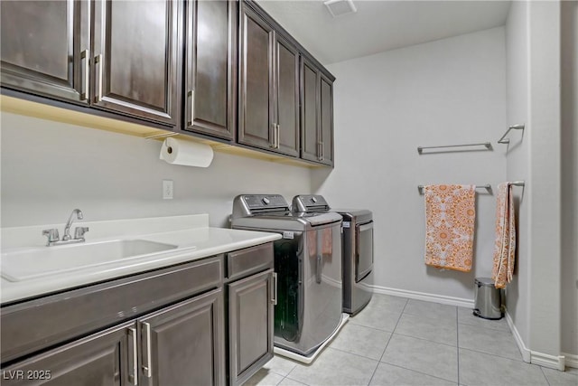 washroom with baseboards, washer and clothes dryer, a sink, cabinet space, and light tile patterned floors
