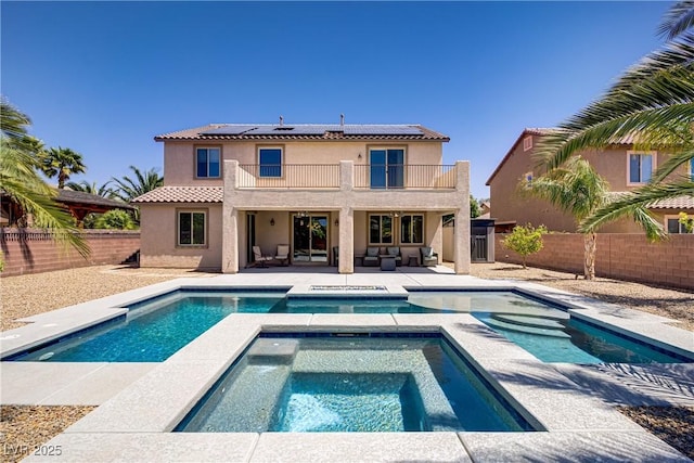 back of property with a balcony, stucco siding, an outdoor living space, roof mounted solar panels, and a patio area