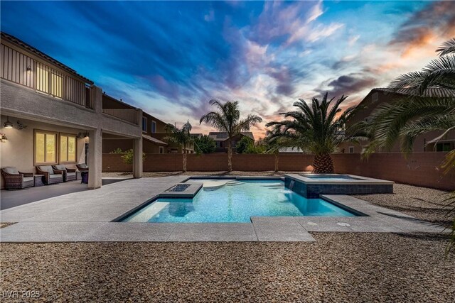 view of pool with a pool with connected hot tub, fence, an outdoor living space, and a patio area