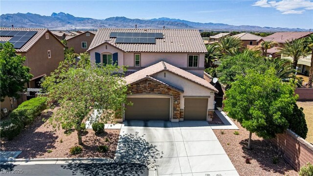 view of front of home with a tile roof, stucco siding, roof mounted solar panels, a mountain view, and concrete driveway
