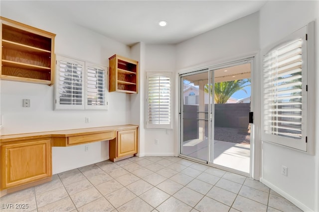 unfurnished dining area with baseboards, recessed lighting, light tile patterned flooring, and built in desk