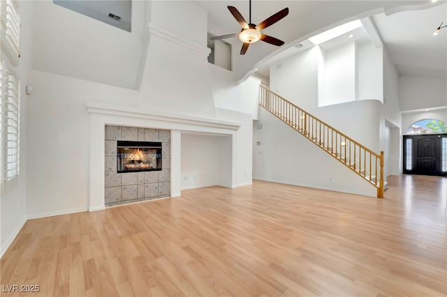 unfurnished living room featuring stairway, a ceiling fan, high vaulted ceiling, and wood finished floors