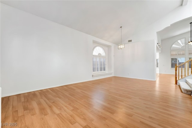 empty room featuring a chandelier, light wood-style floors, visible vents, and stairs