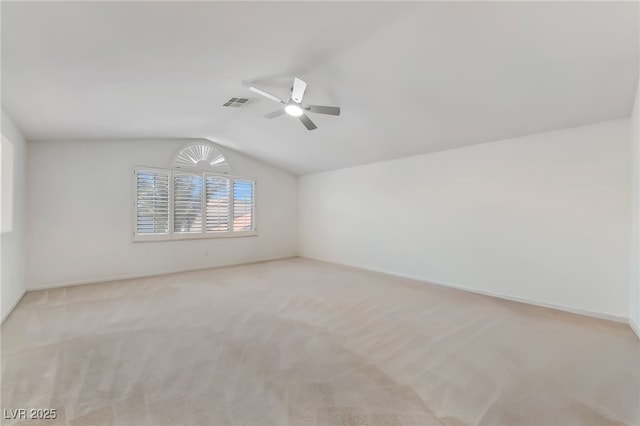 spare room with vaulted ceiling, visible vents, carpet floors, baseboards, and ceiling fan