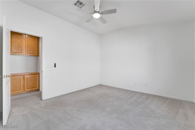 unfurnished room featuring light carpet, vaulted ceiling, visible vents, and ceiling fan