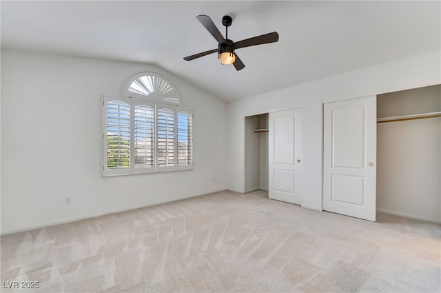 unfurnished bedroom featuring vaulted ceiling, baseboards, carpet, and two closets