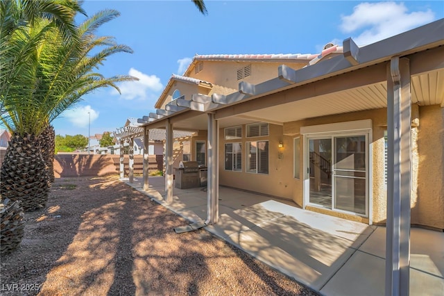 rear view of house with a patio area, stucco siding, and fence