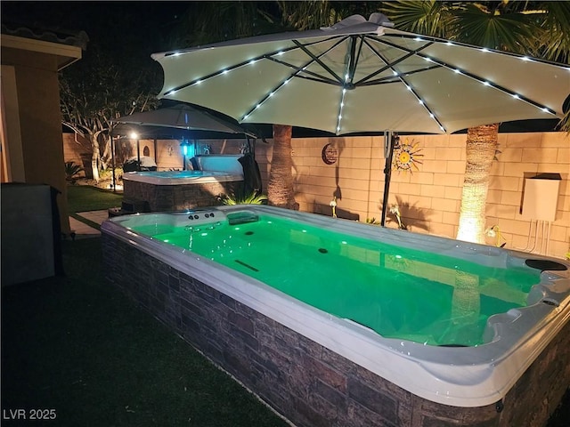 1776 Gentle Brook St, North Las Vegas, NV 89084 - pool at night featuring a fenced backyard and an outdoor hot tub