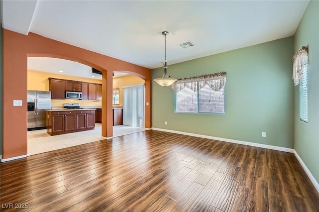 9651 Bouncing Ball St, Las Vegas, NV 89178 - unfurnished living room featuring arched walkways, light wood-type flooring, healthy amount of natural light, and baseboards