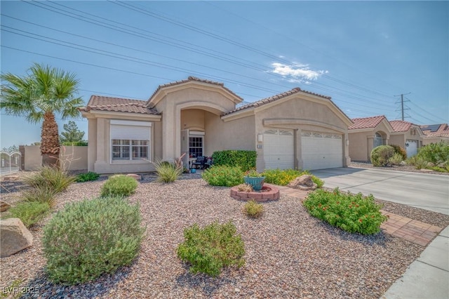 mediterranean / spanish home with concrete driveway, an attached garage, a tiled roof, and stucco siding