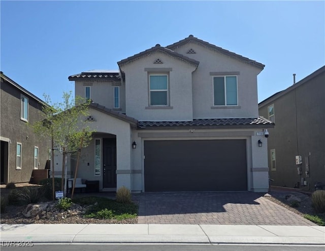 view of front of property with stucco siding, a tiled roof, decorative driveway, and an attached garage