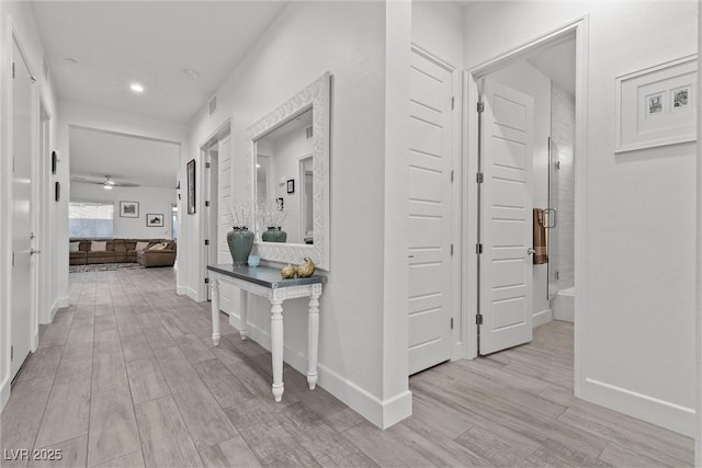 hallway featuring light wood-style flooring, baseboards, visible vents, and recessed lighting