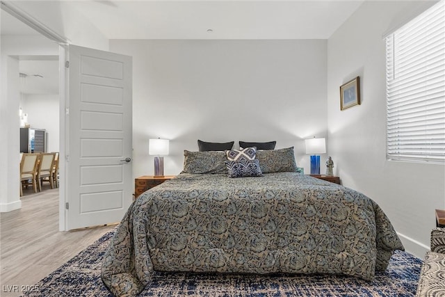 bedroom with multiple windows, baseboards, and wood finished floors