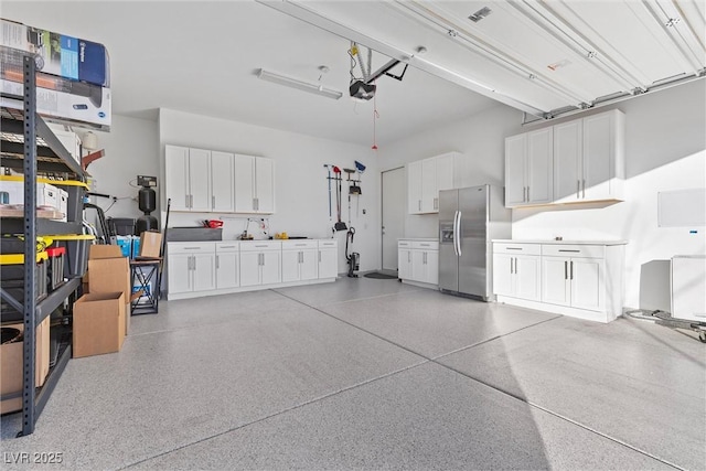 garage featuring stainless steel fridge with ice dispenser and a garage door opener