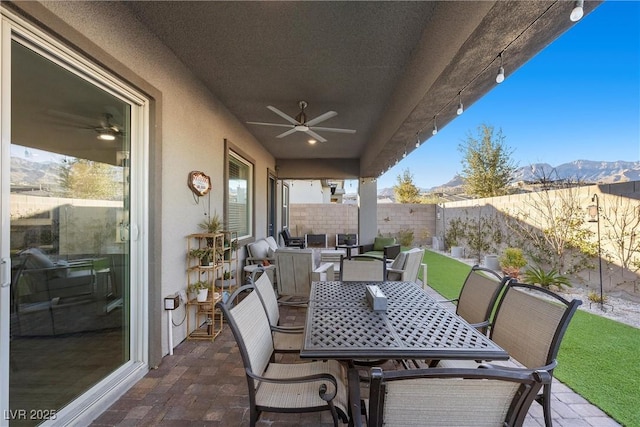 view of patio featuring a mountain view, a fenced backyard, ceiling fan, and outdoor dining space