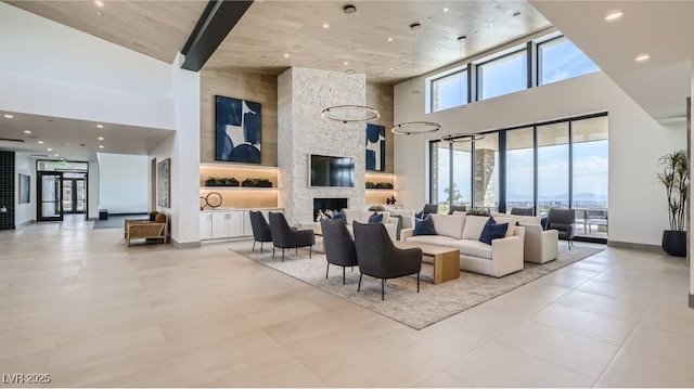 living area with a high ceiling, light tile patterned floors, baseboards, and a stone fireplace