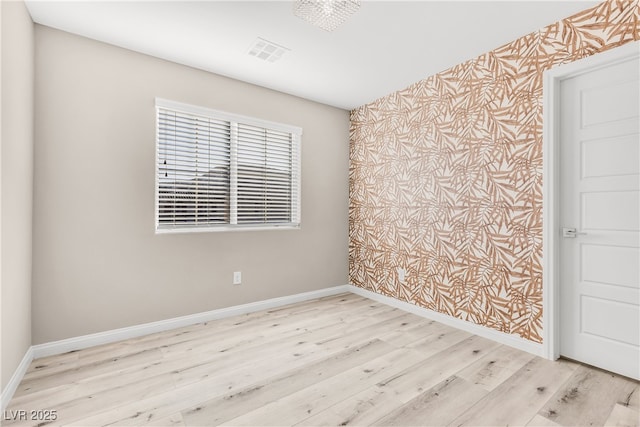 unfurnished room with baseboards, wood finished floors, and visible vents