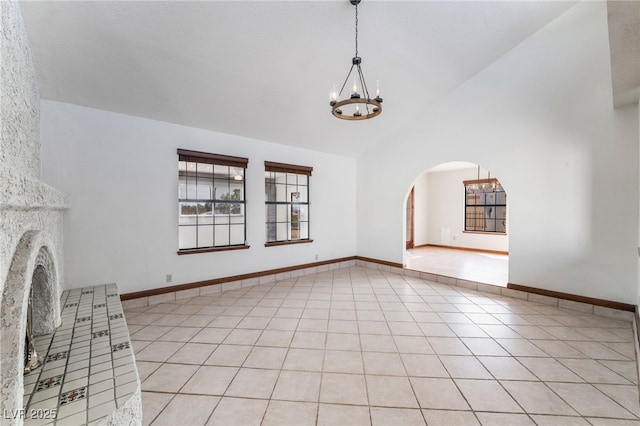 6861 E Washington Ave, Las Vegas, NV 89110 - unfurnished living room featuring a chandelier, arched walkways, high vaulted ceiling, light tile patterned floors, and baseboards
