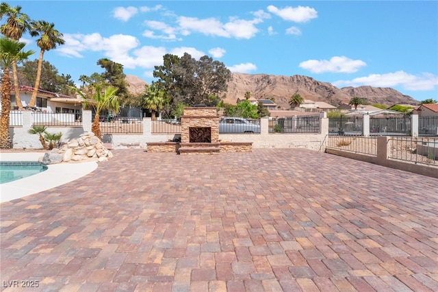 6861 E Washington Ave, Las Vegas, NV 89110 - view of patio featuring fence, a mountain view, and an outdoor stone fireplace
