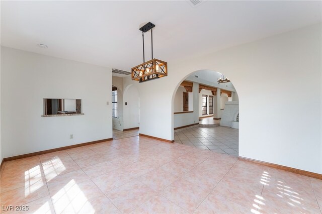 6861 E Washington Ave, Las Vegas, NV 89110 - empty room featuring arched walkways, light tile patterned floors, baseboards, and a chandelier