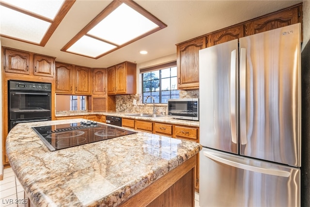 6861 E Washington Ave, Las Vegas, NV 89110 - kitchen with black appliances, a sink, brown cabinetry, decorative backsplash, and a center island