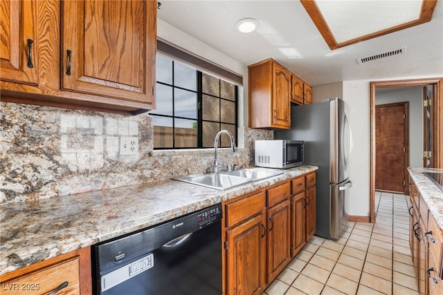 6861 E Washington Ave, Las Vegas, NV 89110 - kitchen with black dishwasher, a sink, stainless steel microwave, backsplash, and brown cabinets