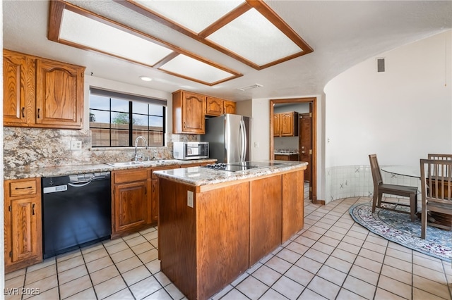 6861 E Washington Ave, Las Vegas, NV 89110 - kitchen with black appliances, a sink, a center island, light tile patterned floors, and brown cabinets