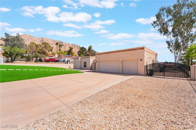 6861 E Washington Ave, Las Vegas, NV 89110 - view of front facade featuring driveway, a gate, a mountain view, a garage, and stucco siding