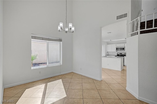 unfurnished dining area with a high ceiling, light tile patterned floors, an inviting chandelier, and visible vents