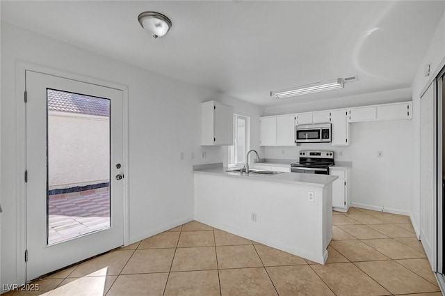 kitchen featuring a peninsula, light countertops, light tile patterned flooring, and appliances with stainless steel finishes