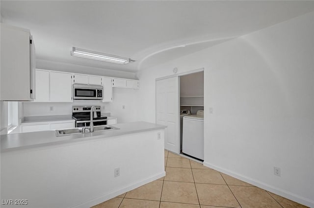 kitchen with a peninsula, light tile patterned floors, light countertops, stainless steel appliances, and a sink