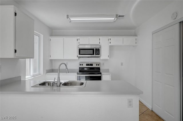 kitchen featuring a sink, light countertops, a peninsula, white cabinetry, and stainless steel appliances