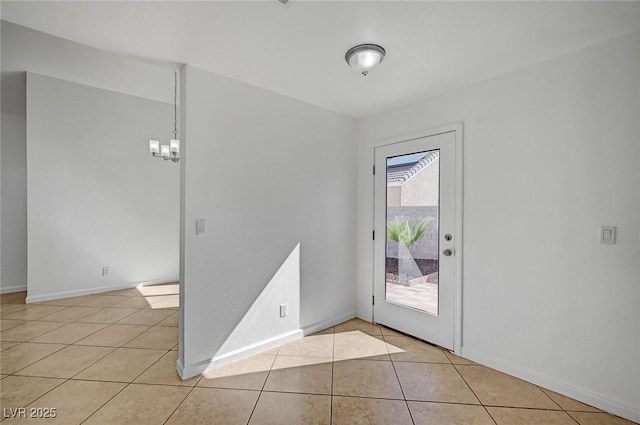 unfurnished room with light tile patterned flooring, baseboards, and an inviting chandelier