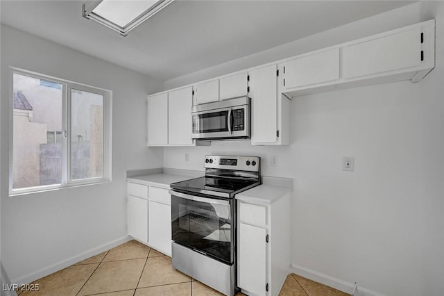 kitchen with light countertops, baseboards, appliances with stainless steel finishes, and light tile patterned flooring