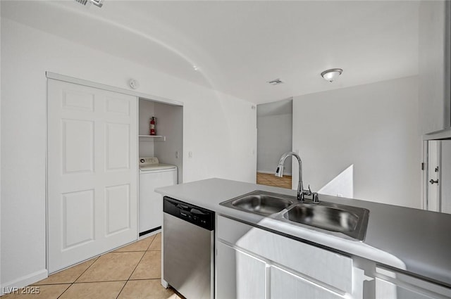 kitchen with light tile patterned floors, visible vents, a sink, stainless steel dishwasher, and washer / dryer