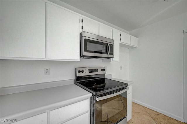 kitchen with light tile patterned floors, white cabinetry, appliances with stainless steel finishes, light countertops, and baseboards