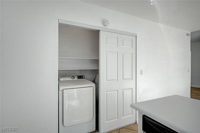clothes washing area with washer / dryer, light tile patterned flooring, and laundry area