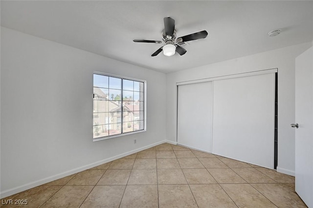 unfurnished bedroom with baseboards, a closet, a ceiling fan, and light tile patterned flooring