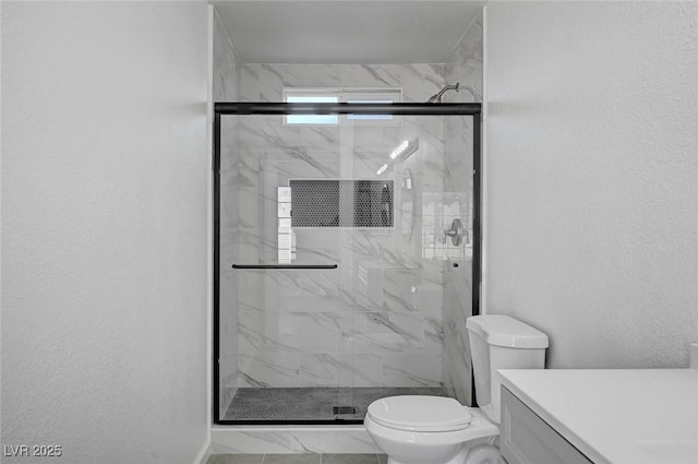 bathroom with toilet, a marble finish shower, and vanity
