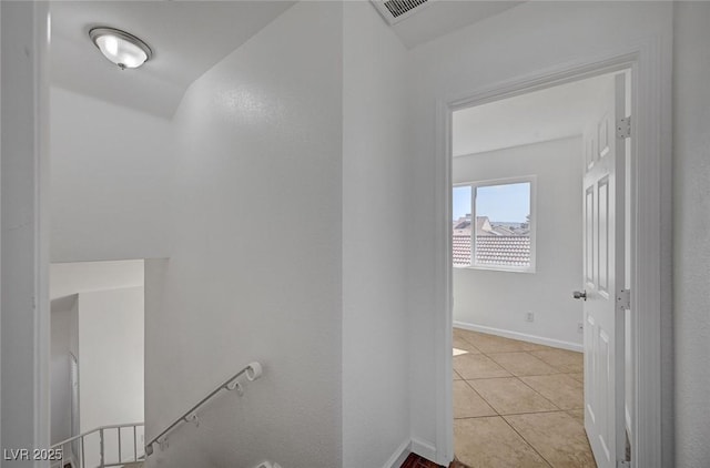 hall featuring light tile patterned floors, baseboards, and visible vents
