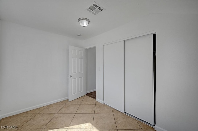 unfurnished bedroom featuring visible vents, baseboards, a closet, and light tile patterned flooring