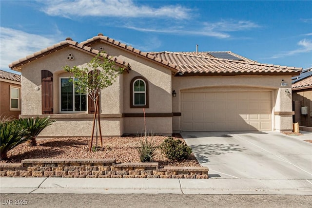 mediterranean / spanish home featuring a garage, driveway, a tiled roof, solar panels, and stucco siding