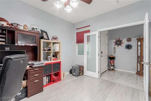 office space with baseboards, a ceiling fan, and light wood-style flooring