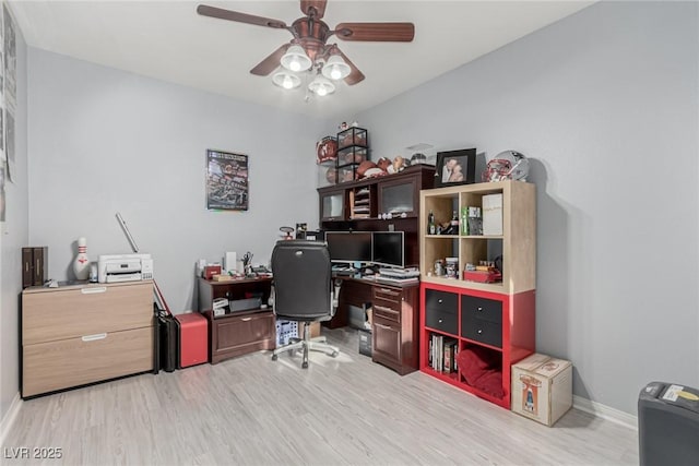 office space featuring baseboards, ceiling fan, and light wood-style flooring