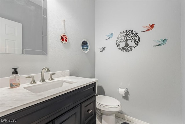 half bath featuring vanity, toilet, and baseboards