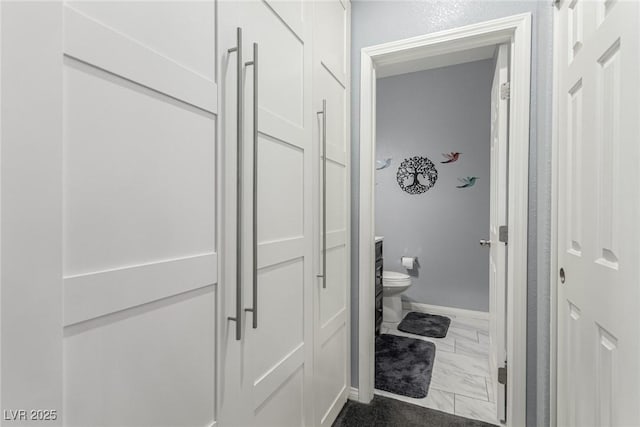 bathroom featuring baseboards, toilet, and marble finish floor
