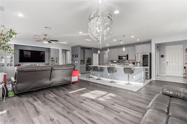 living room with recessed lighting, visible vents, and light wood-type flooring