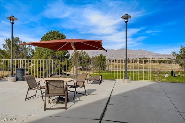 view of patio with outdoor dining area, a mountain view, and fence
