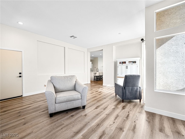 living area featuring baseboards, visible vents, and light wood-style flooring