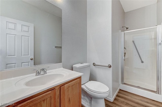 bathroom featuring a shower stall, wood finished floors, toilet, and vanity